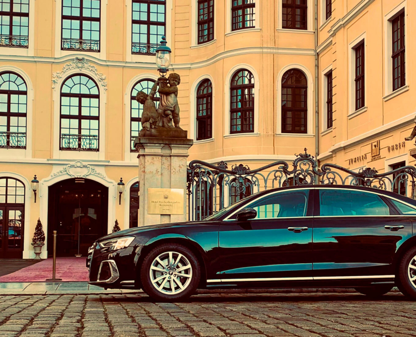 Eine elegante schwarze Limousine parkt auf direkt vor dem Hotel Taschenbergpalais Kempinski in Dresden.