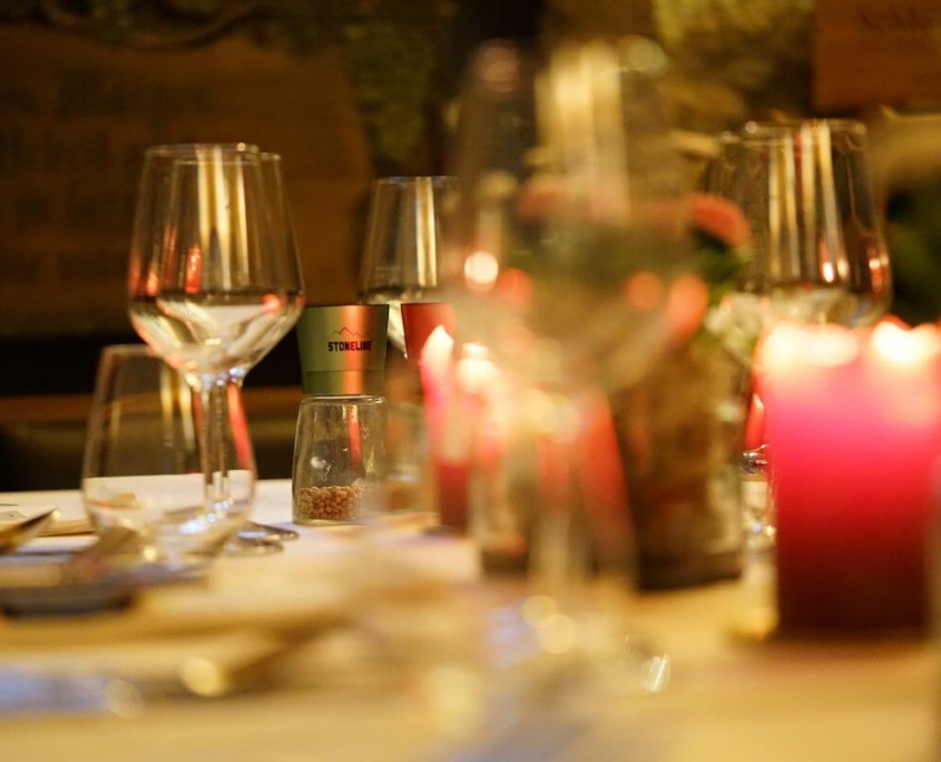 Romantisch gedeckter Tisch im Restaurant Petit Frank Dresden mit Weingläsern, Kerzen und Salz- und Pfefferstreuern.